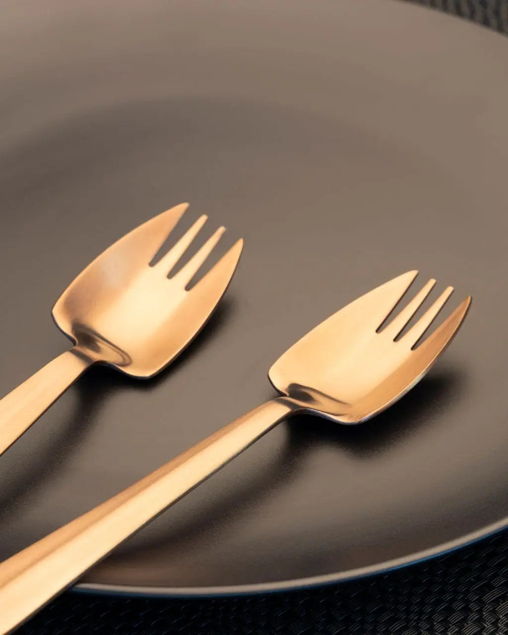 Rose-gold Splayd utensils arranged on a dark plate