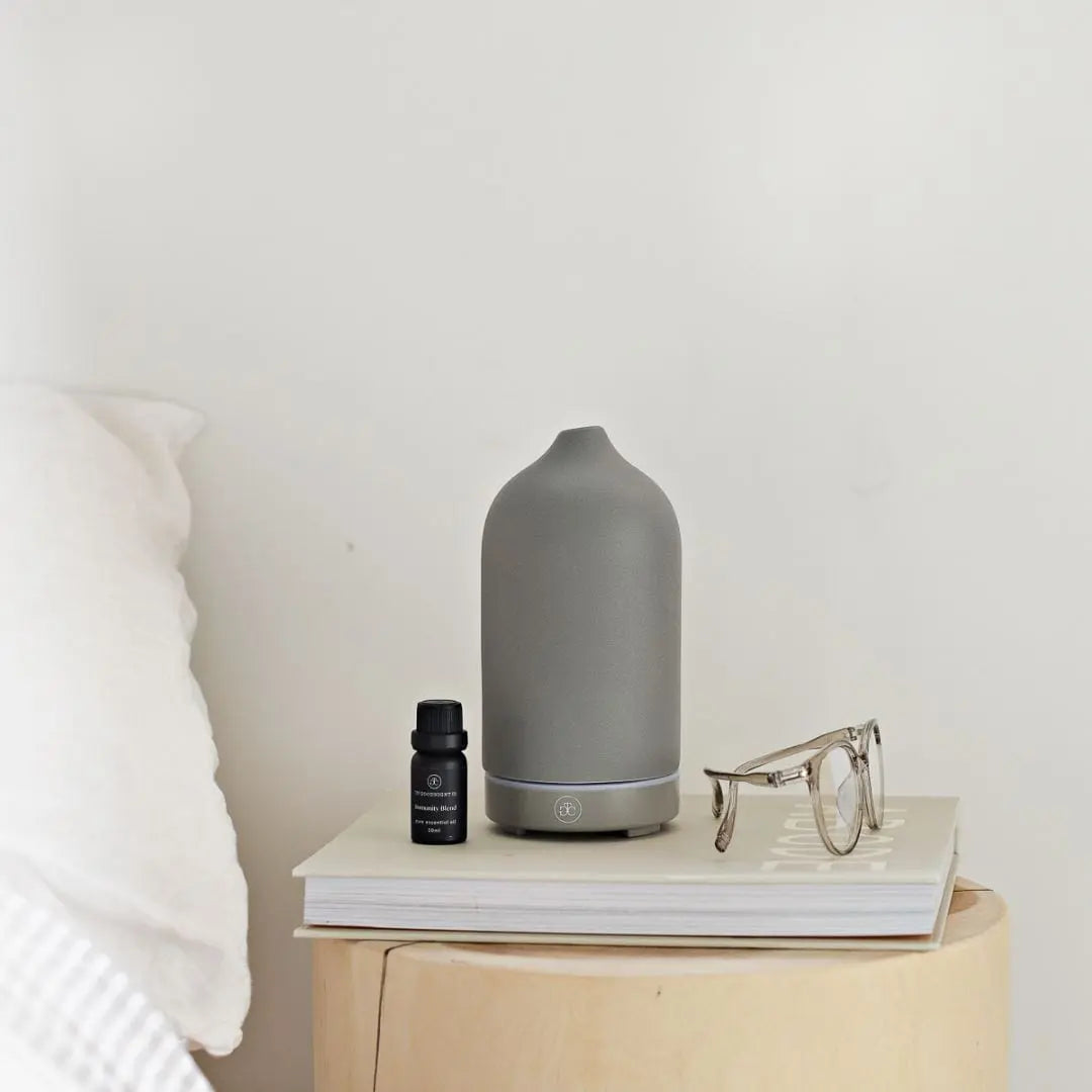 Ceramic ultrasonic diffuser styled on a bedside table with an essential oil bottle