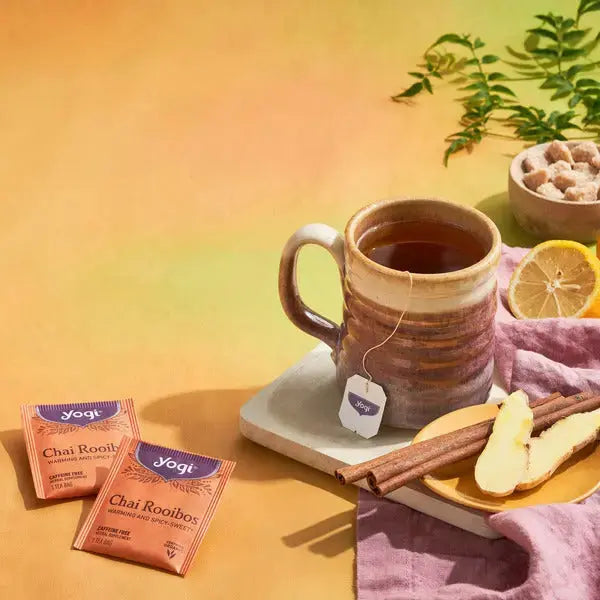 A brewed cup of Yogi chai rooibos tea beside its tea bag box