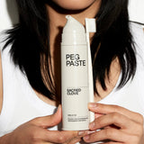 Peg Paste Sacred Clove toothpaste held with a toothbrush