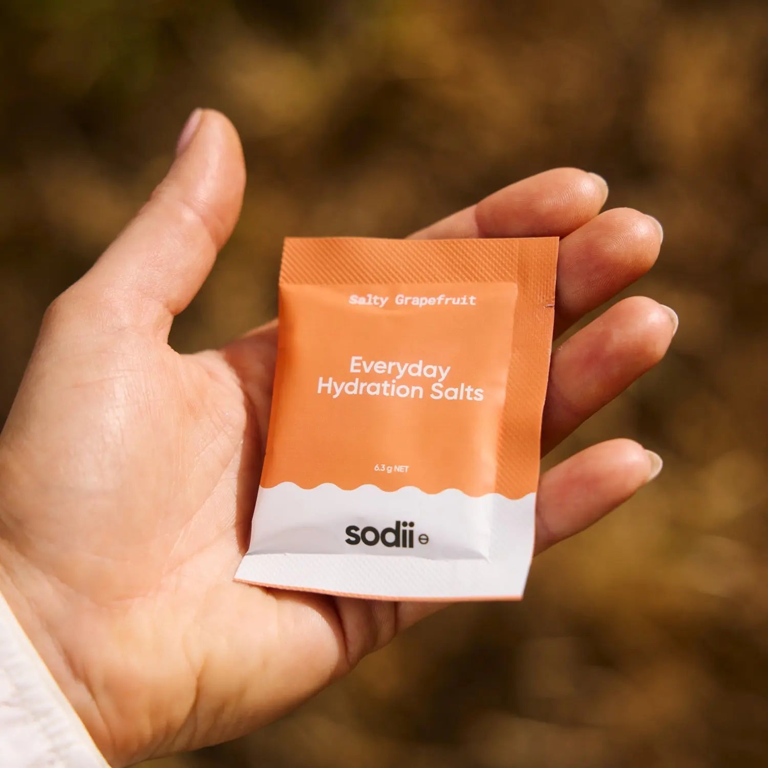 Sodii Salty Grapefruit electrolyte sachet held outdoors